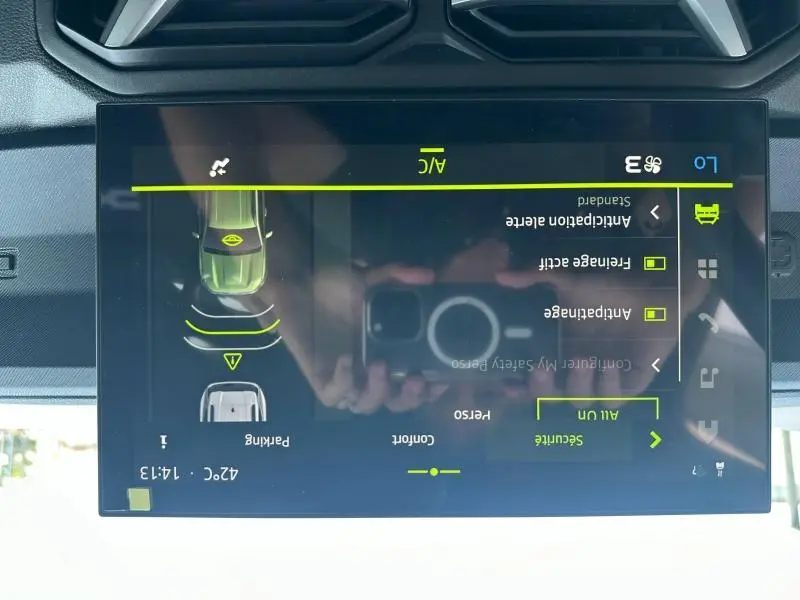 Écran tactile intérieur du Dacia Duster blanc montrant les réglages de sécurité et assistance au stationnement.