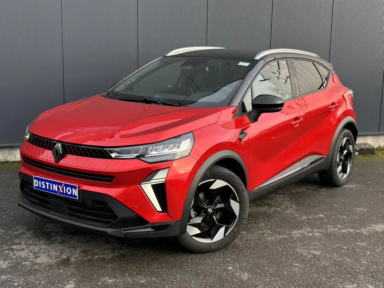 Renault Captur 2025 rouge Flamme et noir, vue 3/4 avant droit, jantes alu noires diamantées et railing de toit alu visibles.