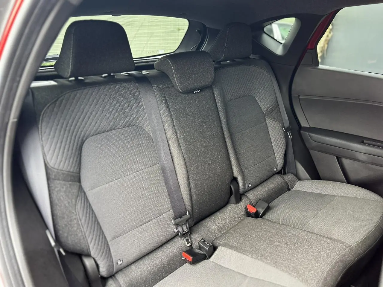 Vue intérieure sur la banquette arrière grise du Renault Captur 2025, avec ceintures et appuie-têtes visibles.