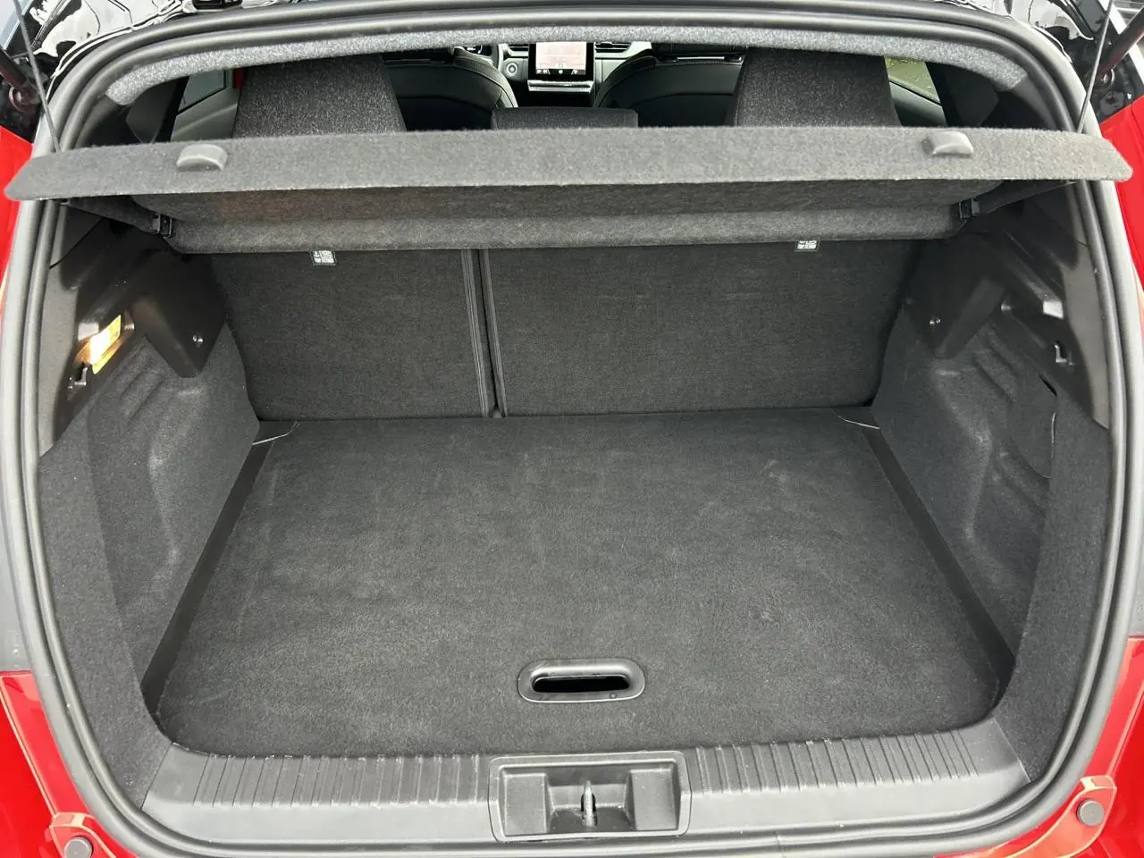 Vue du coffre ouvert du Renault Captur Rouge Flamme, montrant un espace de rangement propre et bien fini.