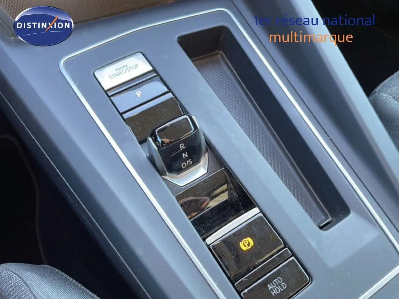 Gros plan sur la console centrale noire de la Volkswagen Golf VIII avec levier de vitesses automatique et bouton start/stop.