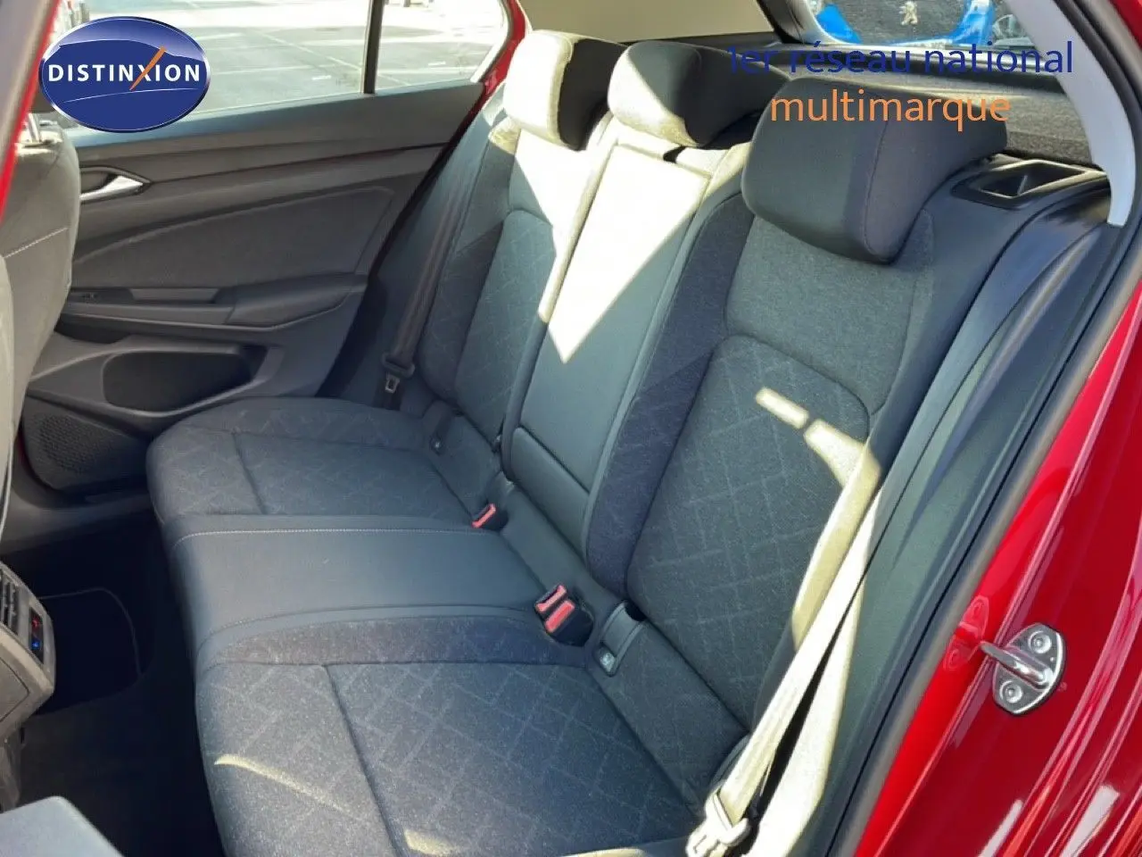 Vue intérieure sur la banquette arrière grise de la Volkswagen Golf VIII rouge Roi Metal, avec ceinture de sécurité visible.