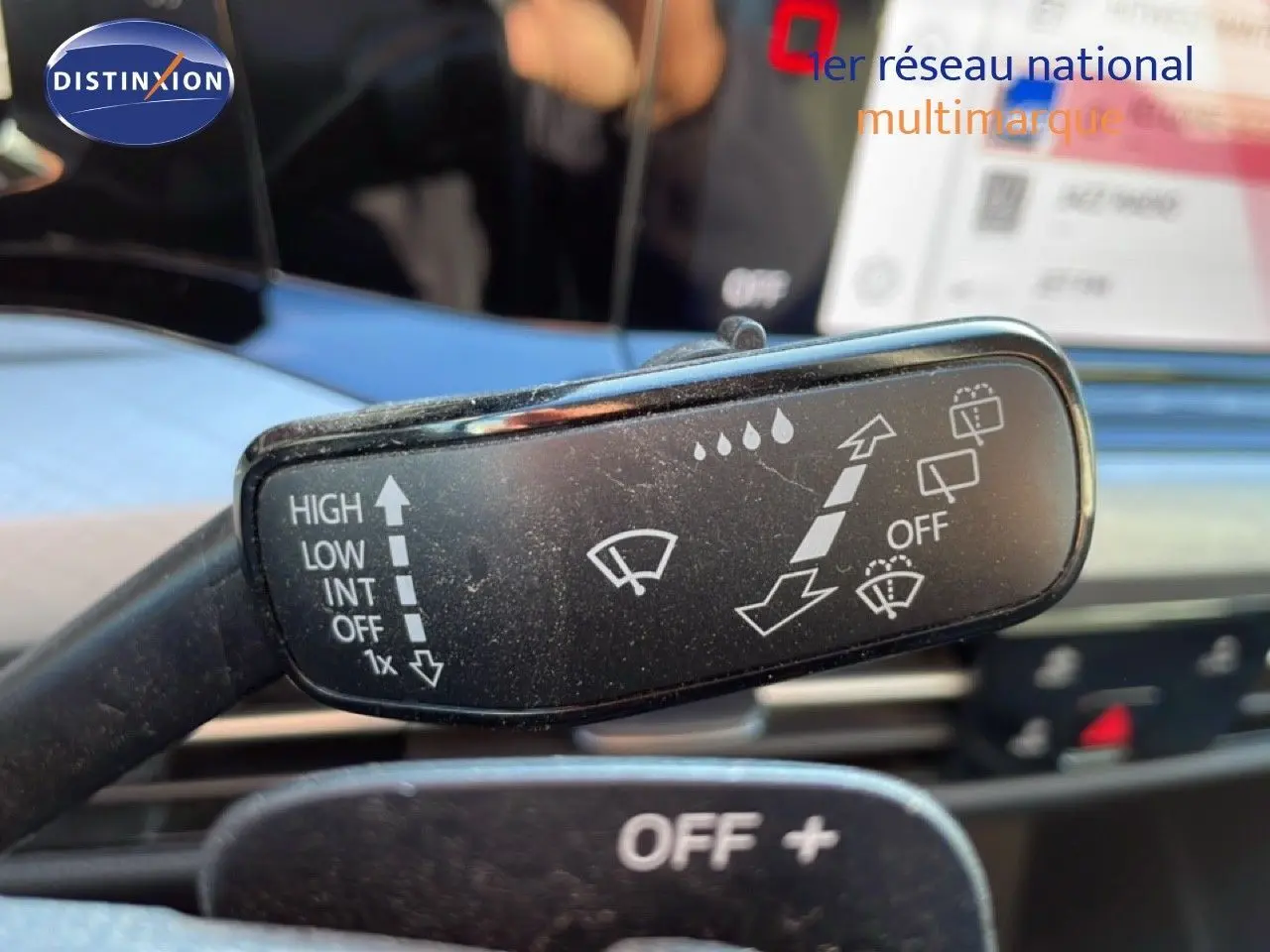 Gros plan sur la commande d’essuie-glace dans l’habitacle d’une Volkswagen Golf VIII rouge, avec tableau de bord flou en arrière-plan.