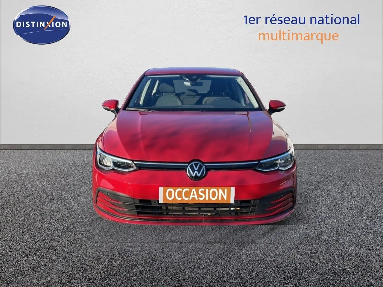 Vue frontale d'une Volkswagen Golf VIII rouge Roi Metal avec calandre noire et phares LED allumés.