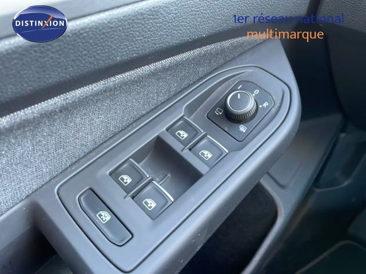 Gros plan sur les commandes de lève-vitres et rétroviseurs côté gauche d’une Volkswagen Golf VIII rouge Roi Metal.