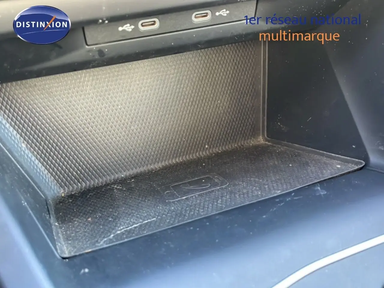 Gros plan sur la console centrale noire de la Volkswagen Golf VIII avec zone de recharge sans fil et ports USB visibles.