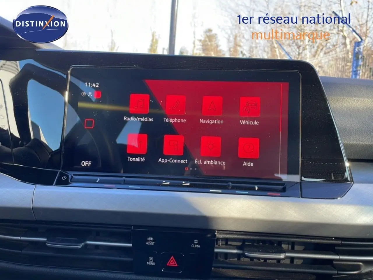 Vue intérieure du tableau de bord de la Volkswagen Golf VIII avec écran tactile affichant le menu multimédia en rouge.