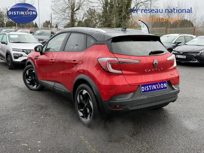Vue 3/4 arrière droite d'un Renault Captur 2025 rouge flamme hybride avec toit noir et jantes noires distinctives.