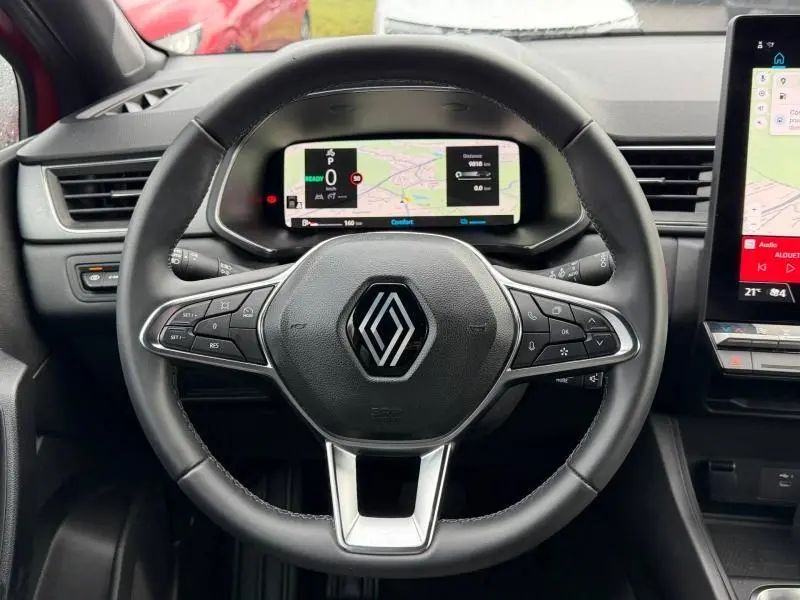 Vue centrée sur le volant du Renault Captur 2025 Rouge Flamme, avec tableau de bord numérique et commandes intégrées.