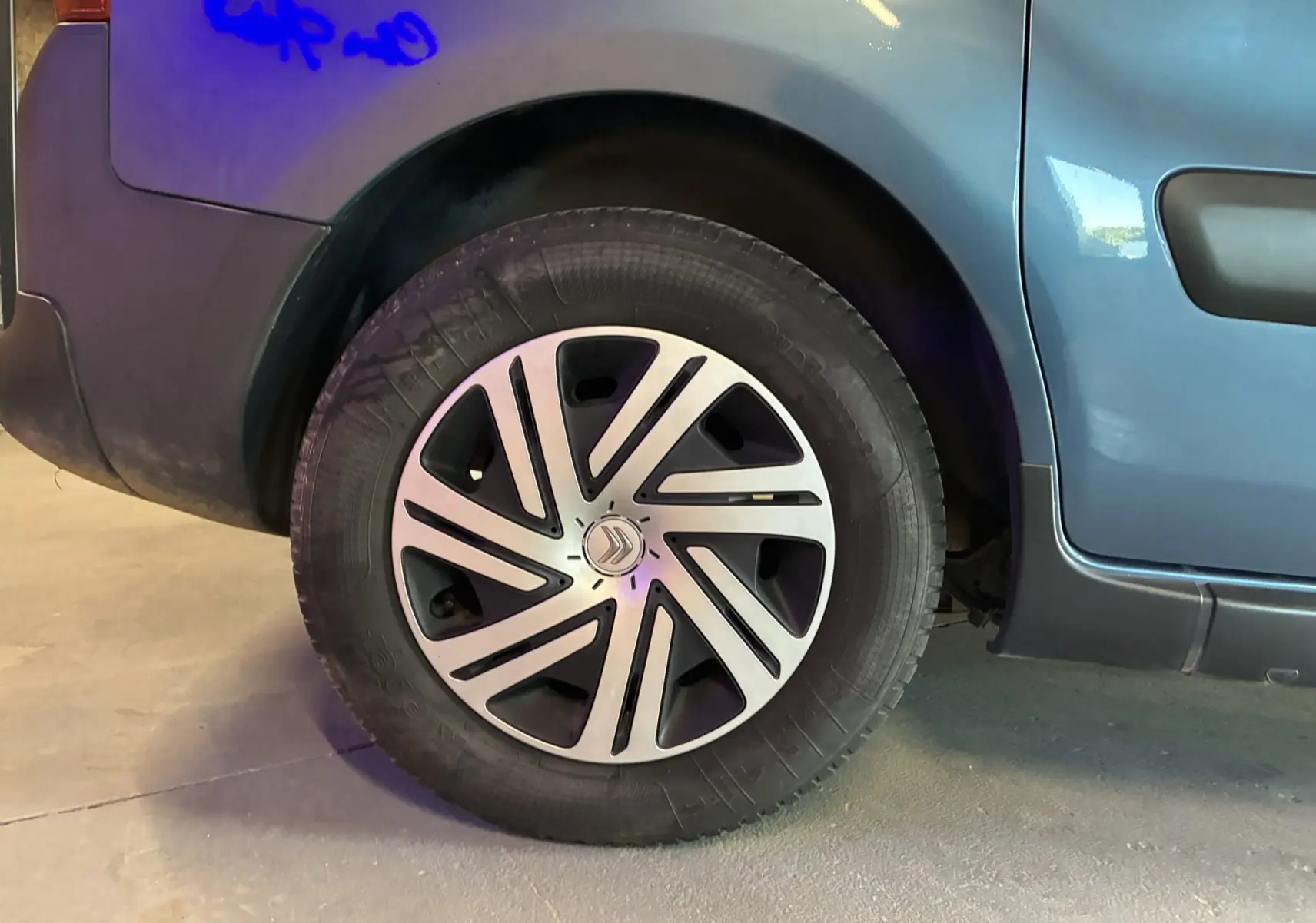 Gros plan sur la roue arrière gauche d’un Citroën Berlingo Multispace bleu, avec jante en alliage au design moderne.
