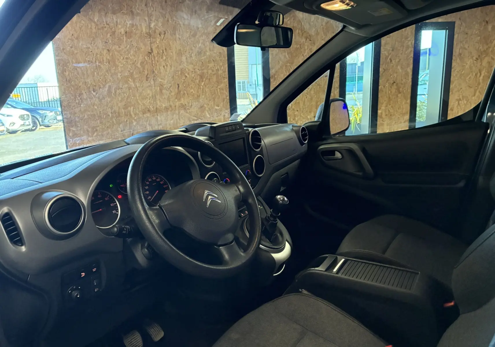 Vue intérieure côté conducteur du Citroën Berlingo Multispace 2017, tableau de bord noir avec volant et levier de vitesse manuels.