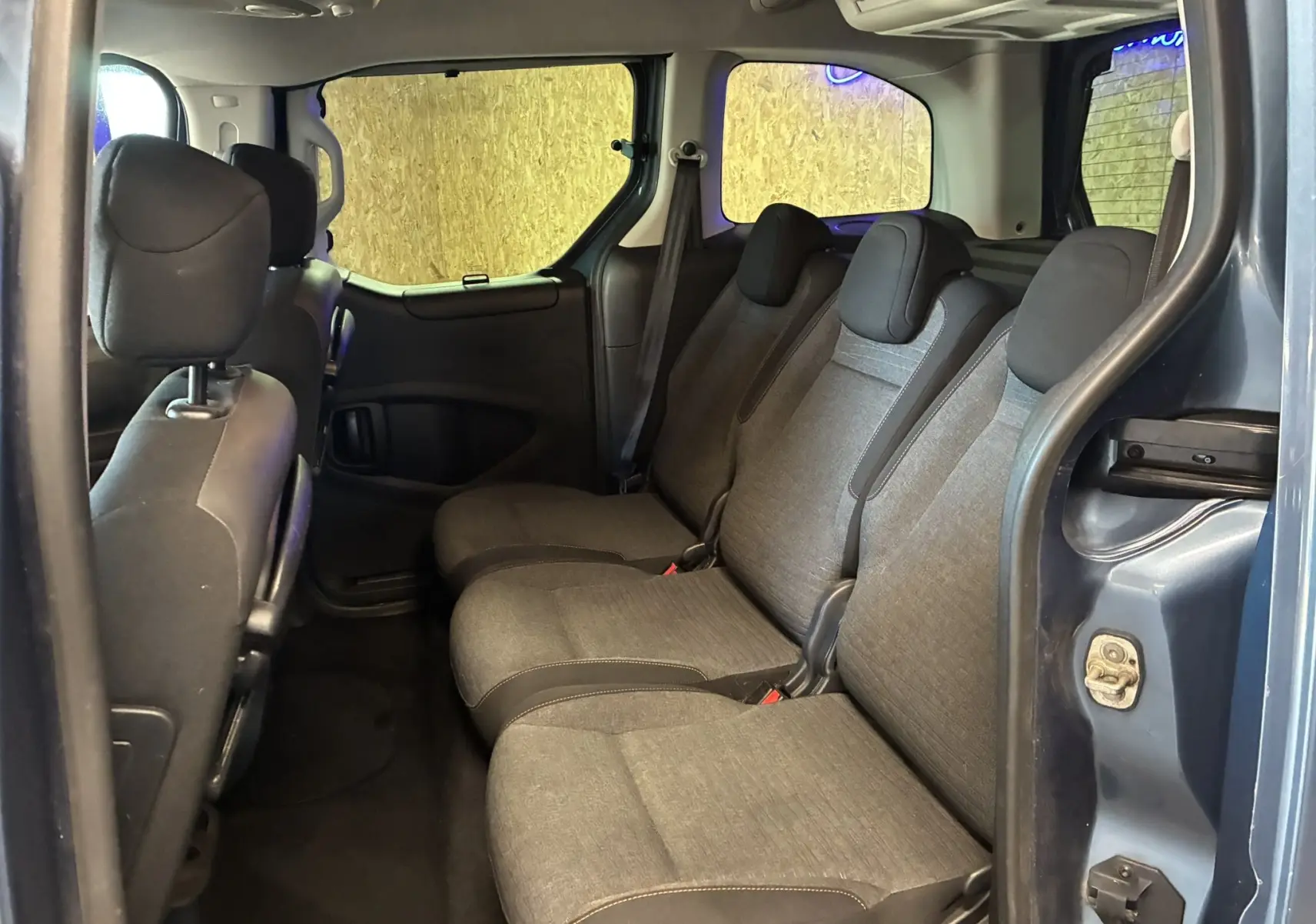 Vue intérieure côté droit montrant la banquette arrière en tissu gris et la porte bleue ouverte du Citroën Berlingo Multispace 2017.