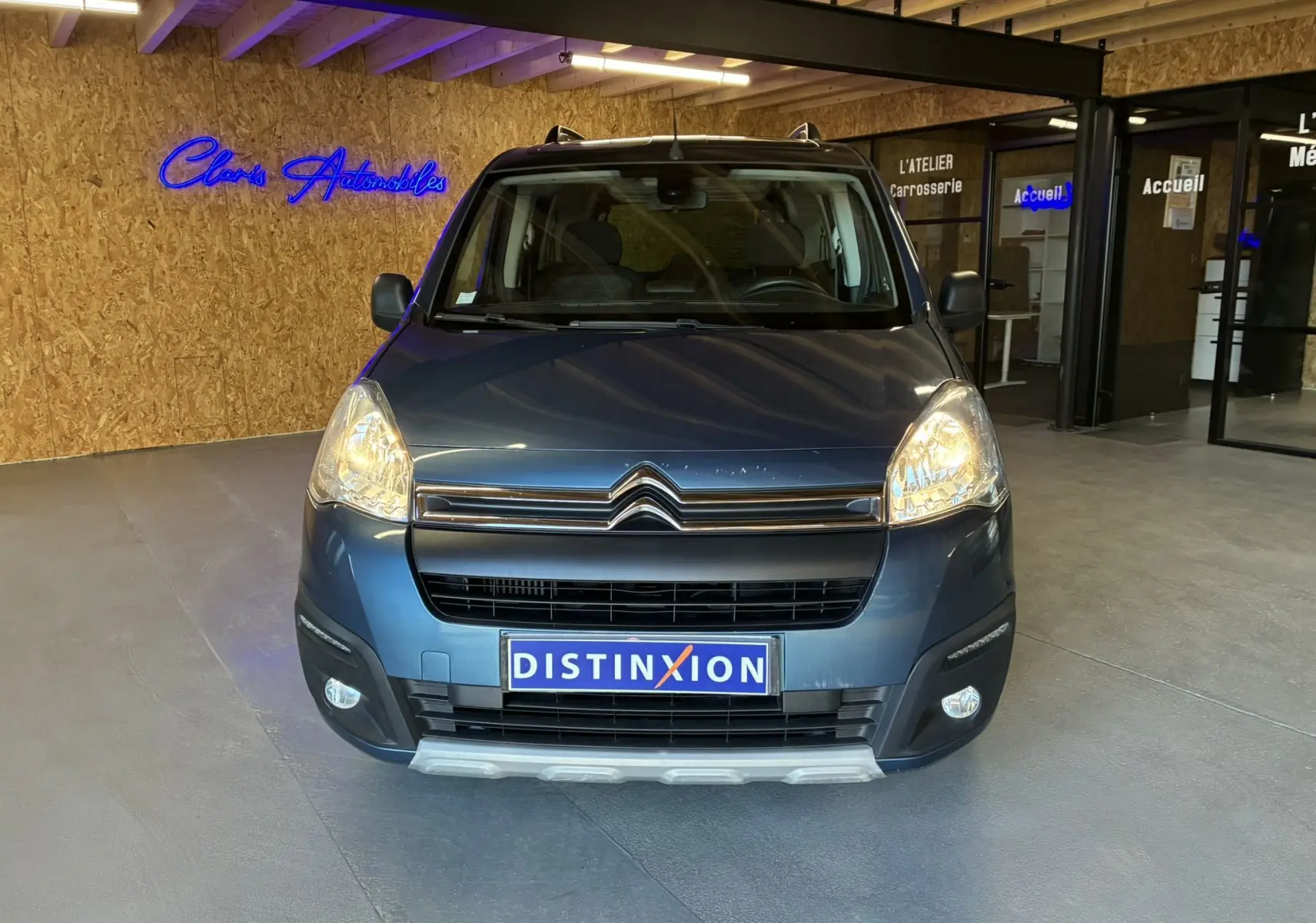 Vue de face d’un Citroën Berlingo Multispace bleu 2017 avec phares allumés dans un showroom intérieur.