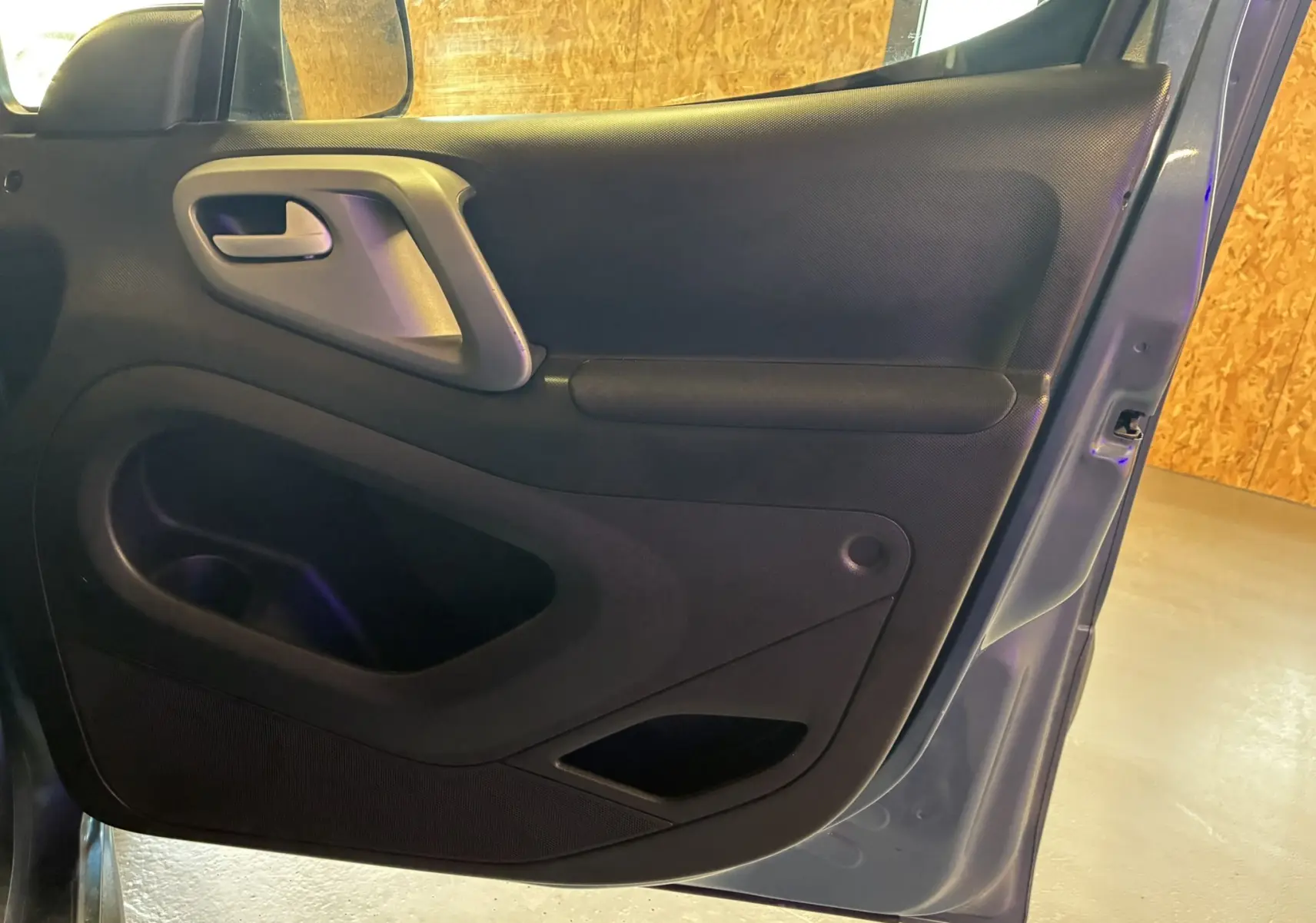 Vue intérieure de la porte avant gauche bleu du Citroën Berlingo Multispace 2017 avec poignée grise et rangement intégré.