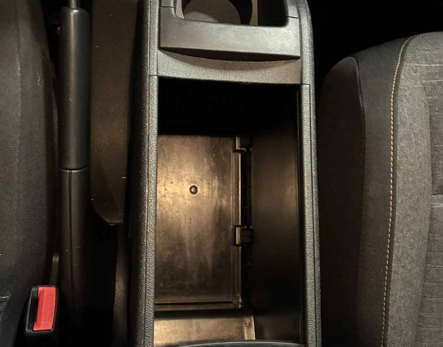 Vue plongeante sur la console centrale noire ouverte entre les sièges avant en tissu gris du Citroën Berlingo Multispace 2017.