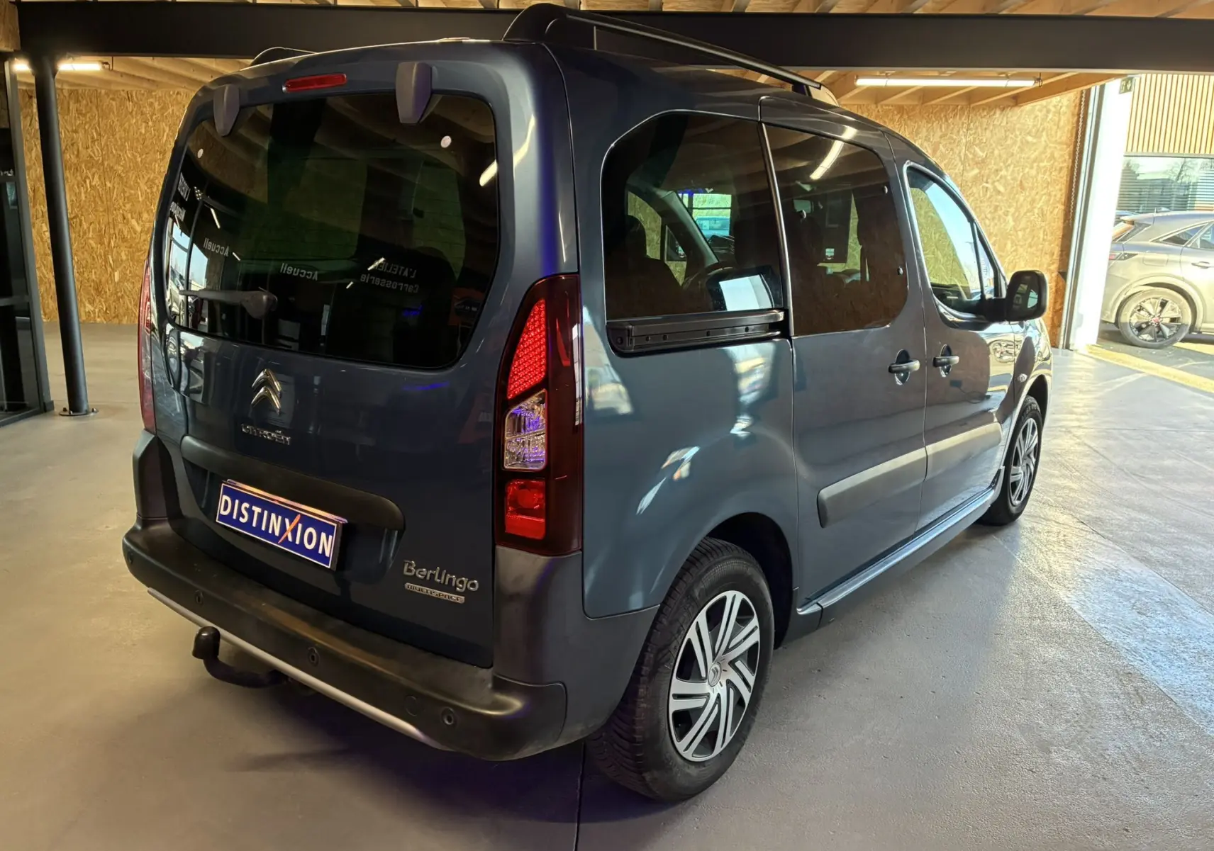 Vue 3/4 arrière droite d’un Citroën Berlingo Multispace bleu 2017 avec hayon et vitres teintées en intérieur.