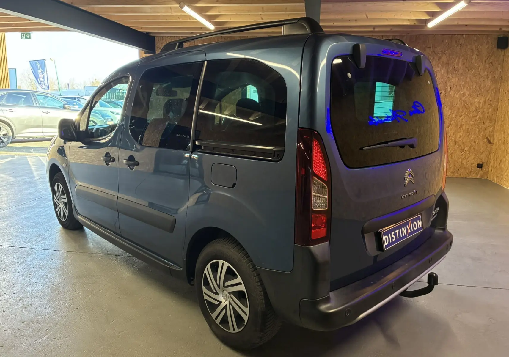 Vue 3/4 arrière droite du Citroën Berlingo Multispace bleu 2017 avec hayon fermé et attelage visible en garage.