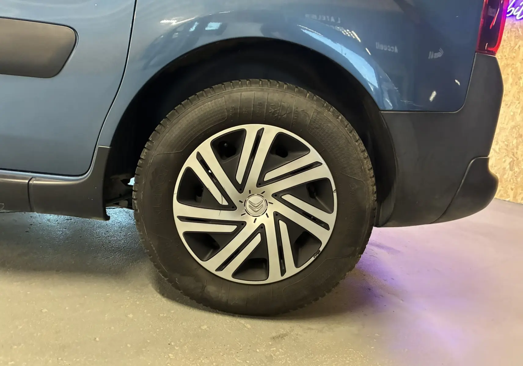 Gros plan sur la roue arrière droite d’un Citroën Berlingo Multispace bleu 2017 avec jante à enjoliveur distinctif.