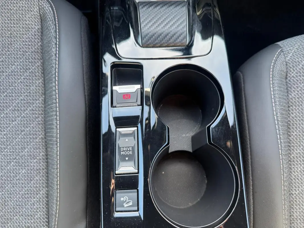 Gros plan sur la console centrale noire du Peugeot 2008 Hybrid 136 e-DCS6 Allure avec commandes Drive Mode et frein à main électrique.