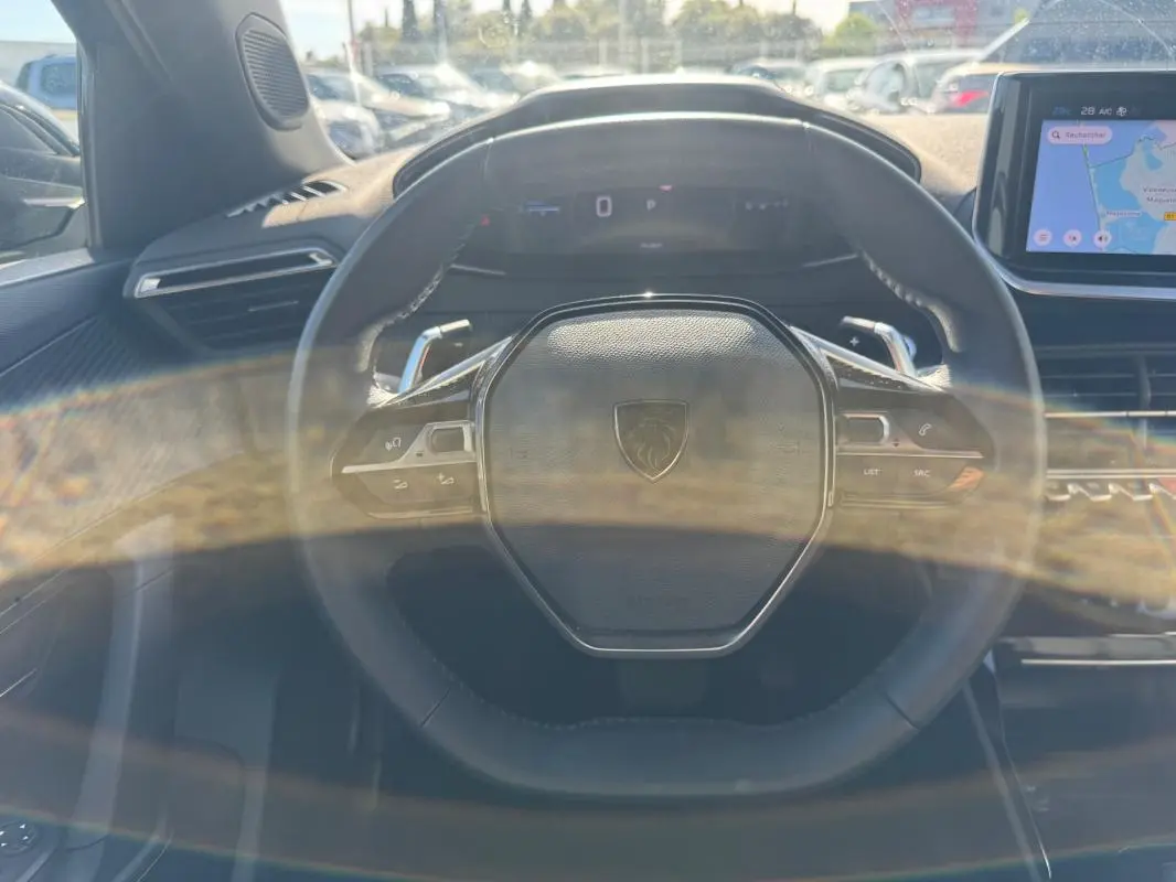 Vue intérieure centrée sur le volant noir du Peugeot 2008 Hybrid 136 e-DCS6 Allure avec écran tactile et cockpit numérique.