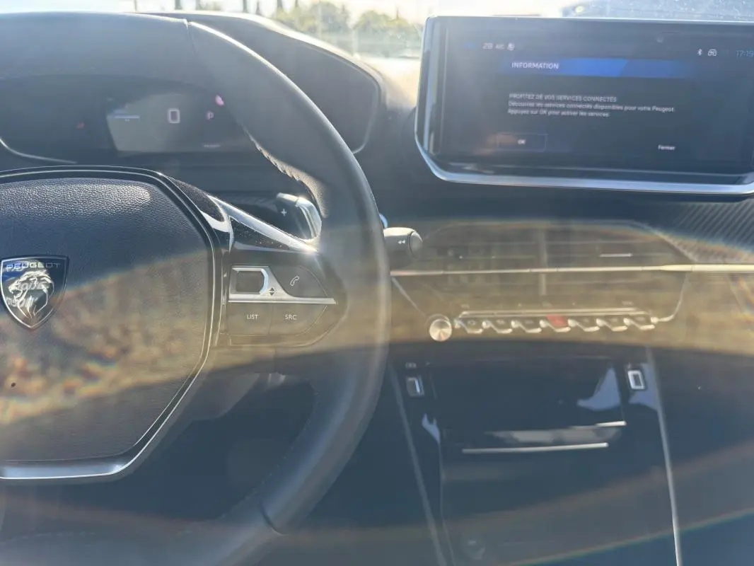 Intérieur du Peugeot 2008 Hybrid 136 Allure 2025 vu du poste de conduite, avec volant multifonction et écran tactile central.