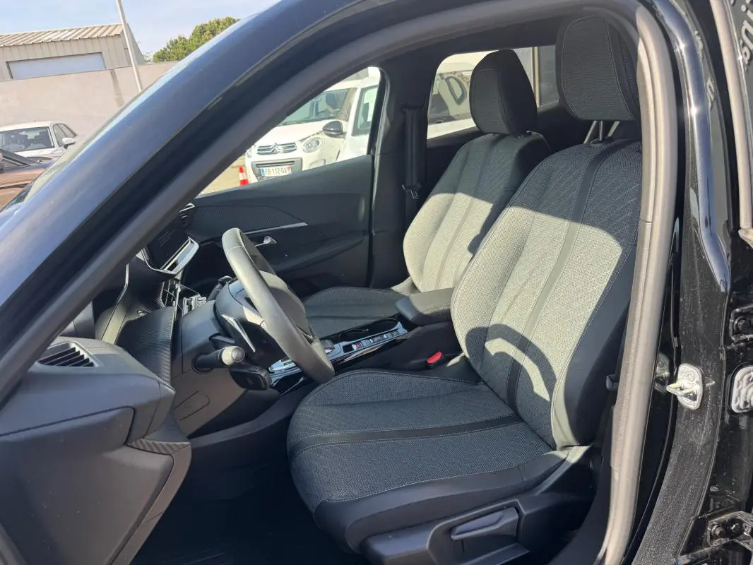 Vue intérieure côté conducteur du Peugeot 2008 Hybrid noir 2025, montrant les sièges avant et le volant.