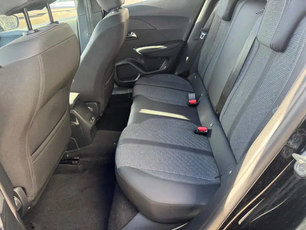 Vue côté droit de la banquette arrière noire et grise du Peugeot 2008 Hybrid 136 e-DCS6 Allure 2025 avec ceintures rouges.