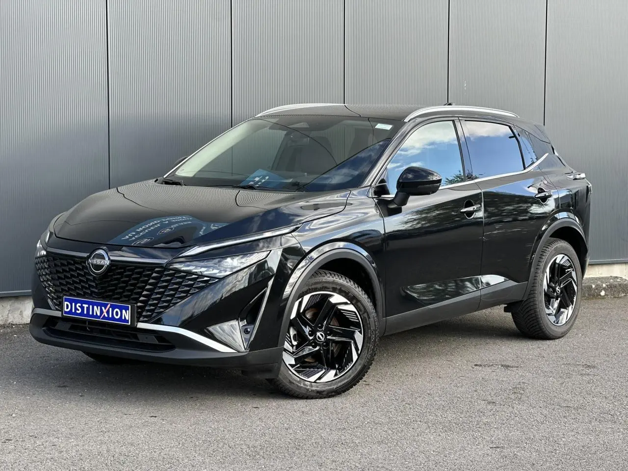 Nissan Qashqai noir nacré en 3/4 avant droit, avec jantes alliage noires et toit panoramique.