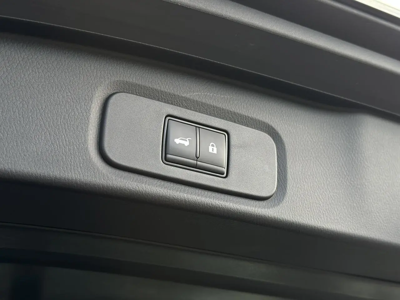 Gros plan sur les boutons du hayon électrique et de verrouillage du coffre du Nissan Qashqai noir nacré.