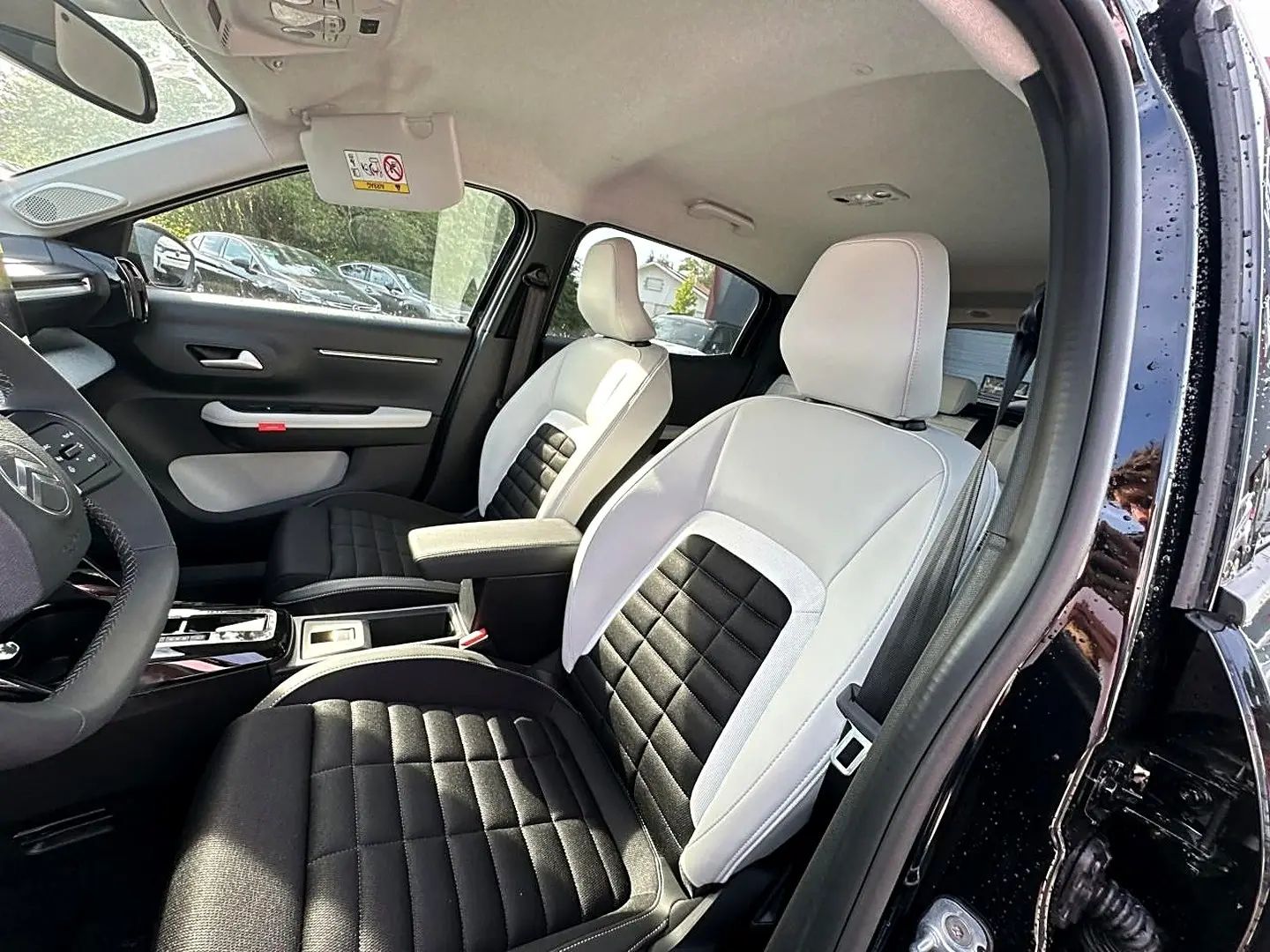 Vue intérieure côté conducteur du Citroën C3 Aircross noir 2026, sièges bicolores noir et blanc avec accoudoir central.