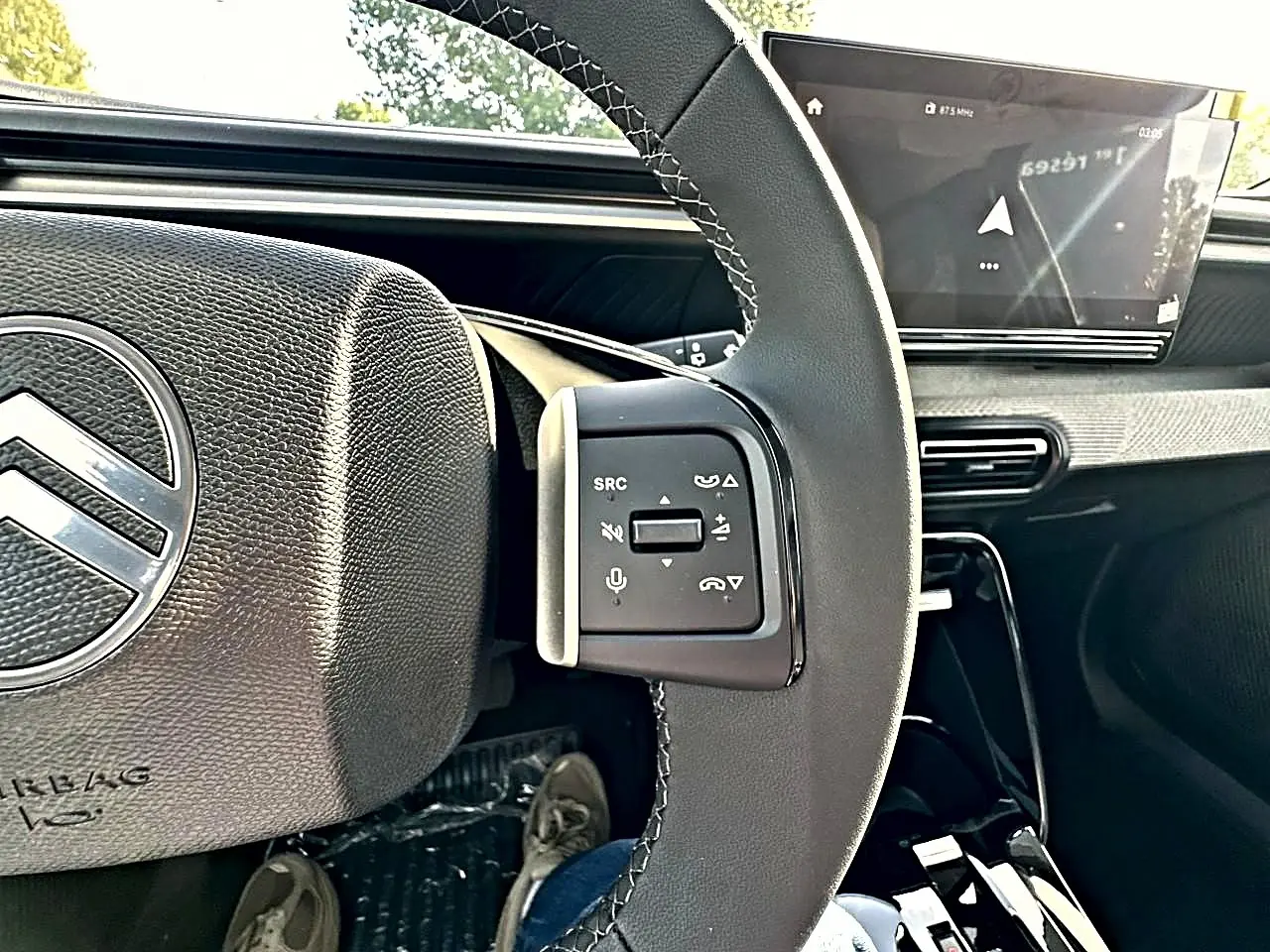 Vue rapprochée du volant noir de la Citroën C3 Aircross 2026, avec commandes audio et écran tactile en arrière-plan.