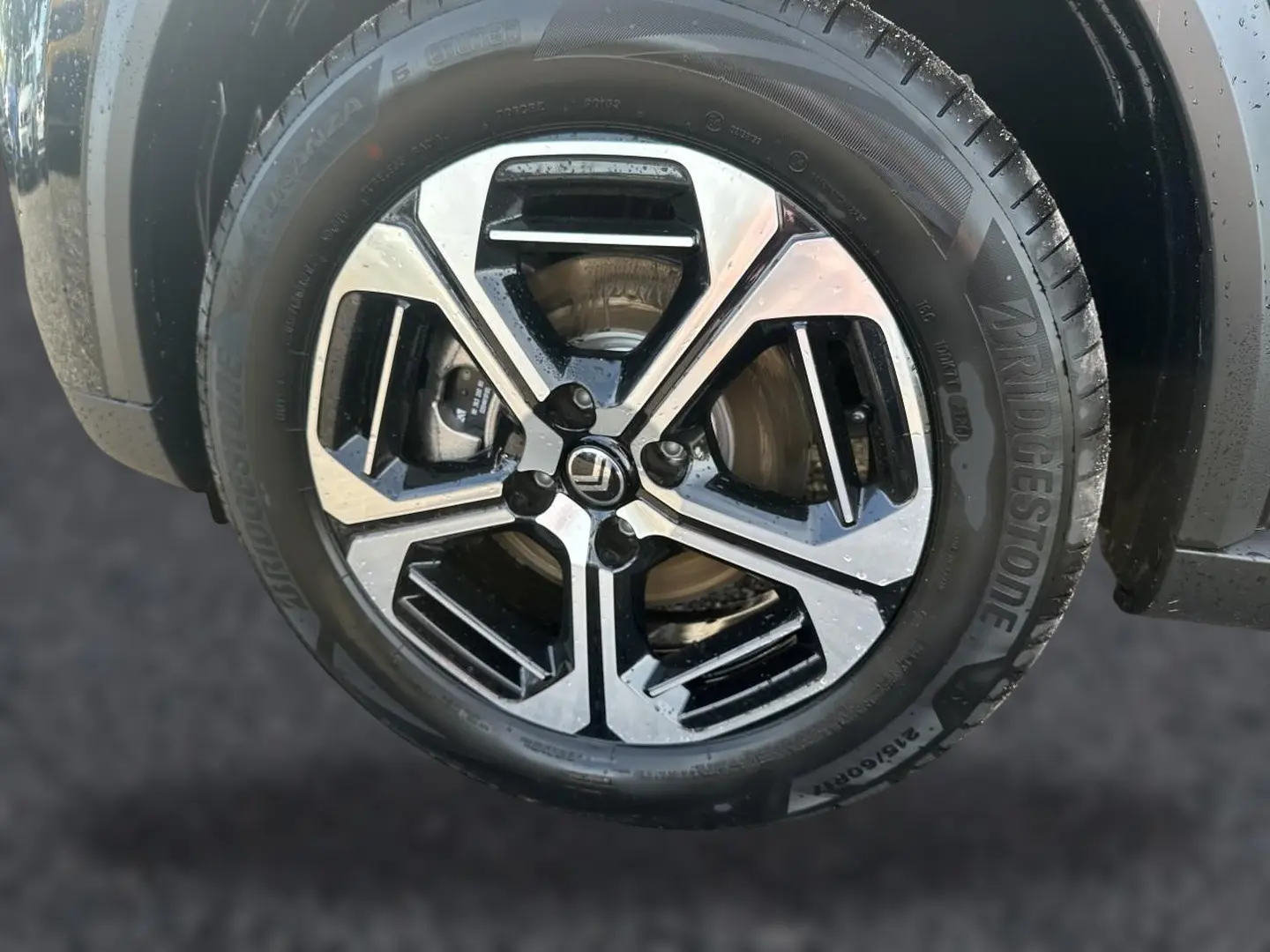 Gros plan sur la jante alu noire et argentée d'une Citroën C3 Aircross noire, vue côté droit.