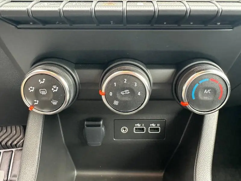 Gros plan sur les commandes de climatisation et ventilation de la Renault Clio Gris Rafale, avec ports USB et prise jack.