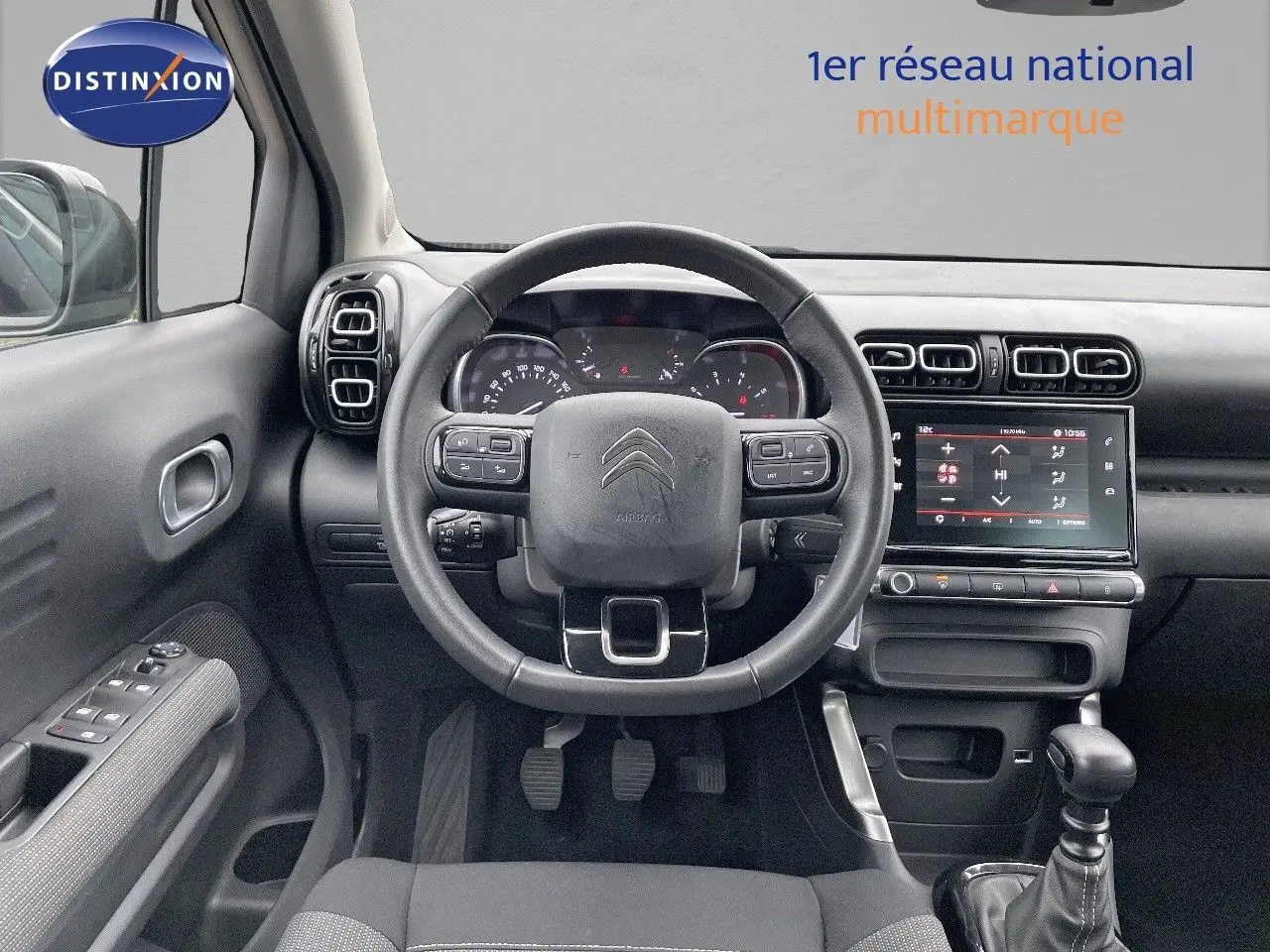 Vue intérieure centrée sur le tableau de bord et le volant d'une Citroën C3 Aircross 2023 noir perle métal avec boîte manuelle.