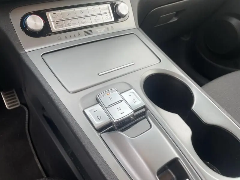 Vue rapprochée de la console centrale du Hyundai Kona électrique 2021, avec commandes de boîte automatique et porte-gobelets.