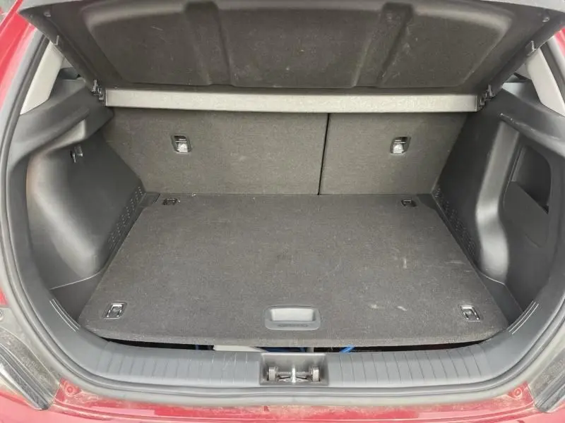 Coffre ouvert vu de l'arrière d'un Hyundai Kona électrique rouge métal 2021, montrant un espace de chargement vide.