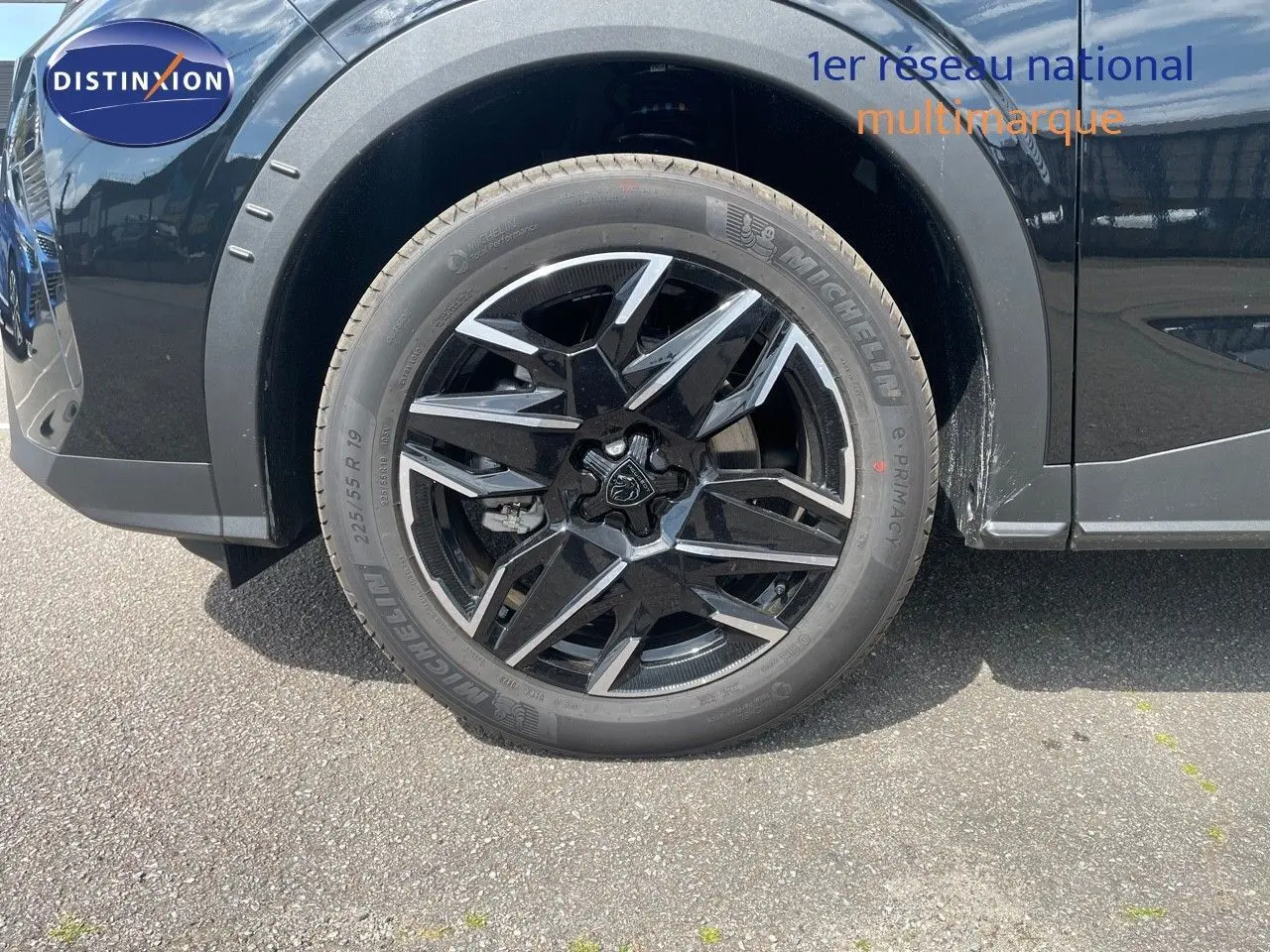 Gros plan sur la roue avant gauche noire métal du Peugeot 5008 Hybrid 136ch GT avec jante alliage bicolore.