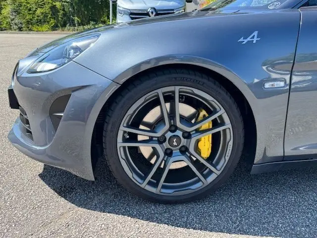 Gros plan sur la roue arrière droite d'une Alpine A110 gris acier avec étrier de frein Brembo jaune et jante alu 18'' Fuchs.