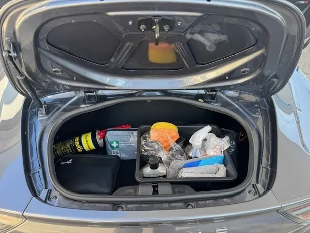 Vue rapprochée de la console centrale en carbone brillant de l'Alpine A110 1.8T 252 Légende avec surpiqûres bleues sur cuir noir.