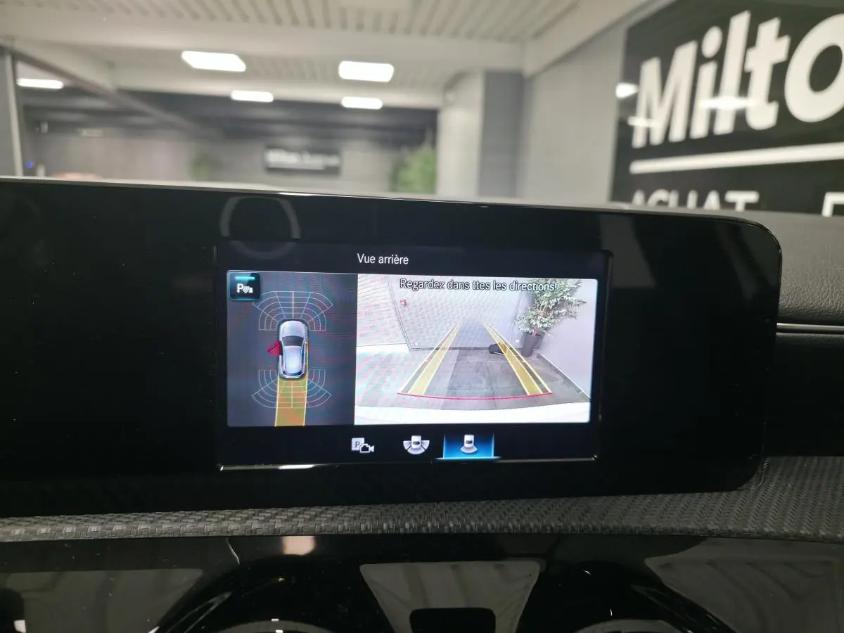 Écran multimédia affichant la caméra de recul et l’aide au stationnement du Mercedes Classe A blanc, vue intérieure centrale.