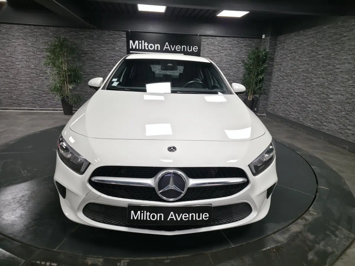 Vue frontale d'une Mercedes Classe A 160 Style Line blanche avec calandre diamant et logo central dans un showroom.