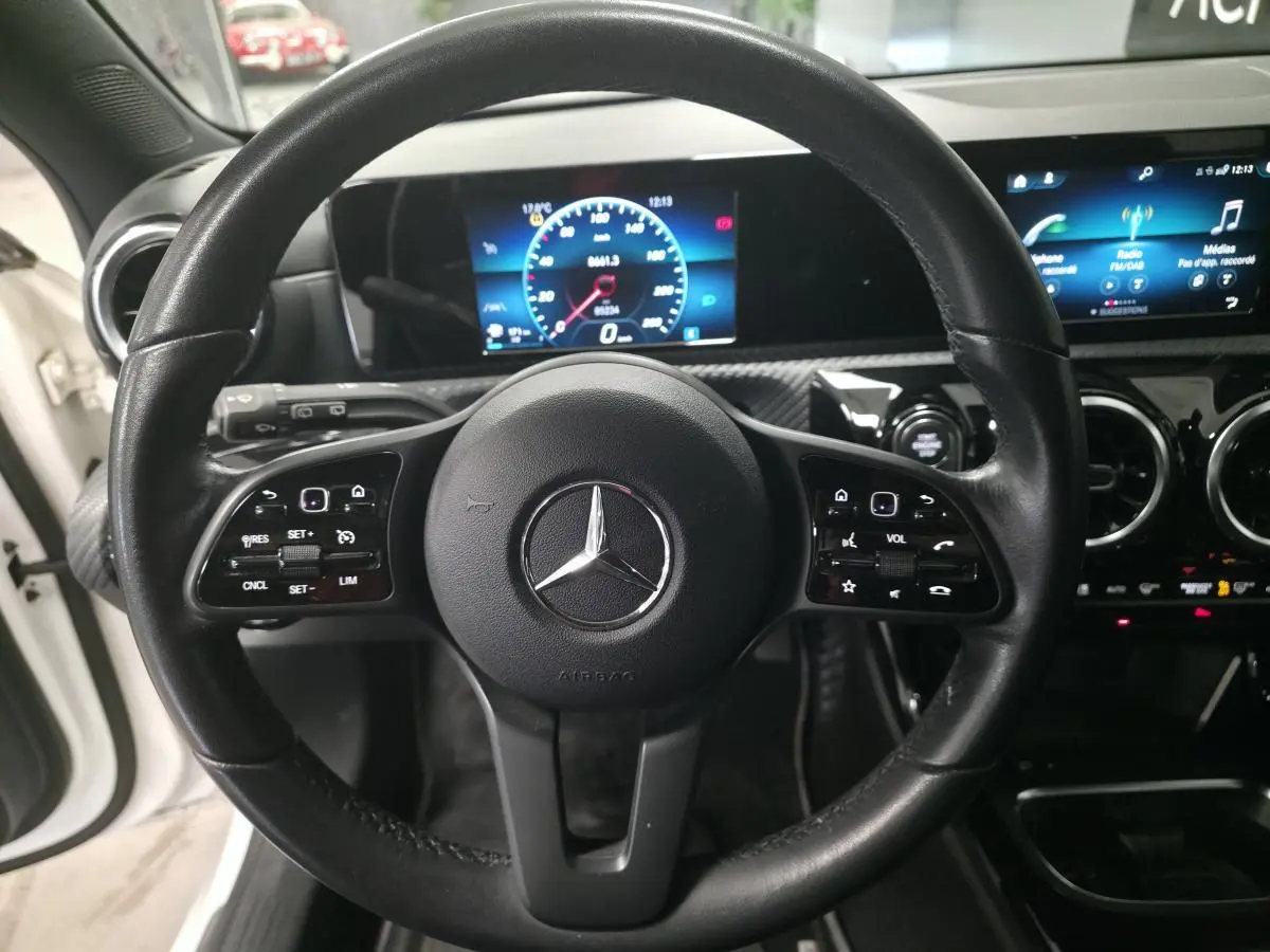 Vue rapprochée du volant cuir noir de la Mercedes Classe A 160 Style Line 2019 avec tableau de bord digital et écran tactile.