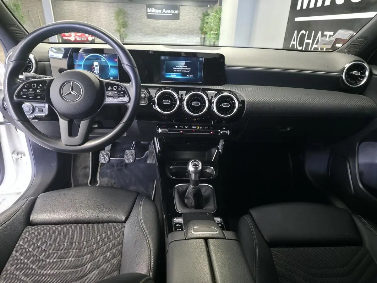 Intérieur noir de la Mercedes Classe A 160 Style Line 2019, vue avant centrée sur le tableau de bord et la boîte manuelle.