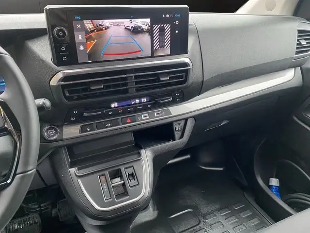 Vue intérieure du tableau de bord du Citroën Jumpy XL blanc, avec écran tactile affichant la caméra de recul et commandes climatisation.