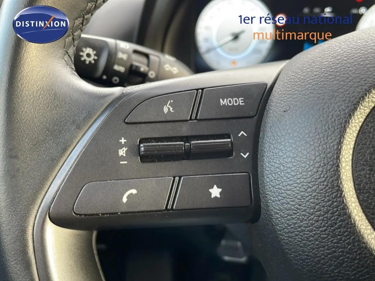 Gros plan sur les commandes au volant noir de la Hyundai i20 2025 Bleu Vibrant Metal, avec boutons de volume et mode.