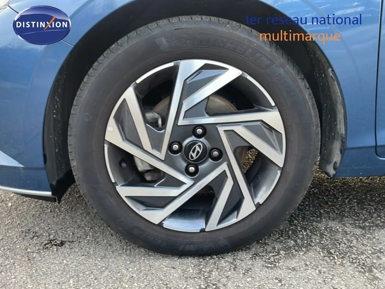 Gros plan sur la roue avant gauche d'une Hyundai i20 Bleu Vibrant Metal, mettant en valeur la jante au design géométrique.