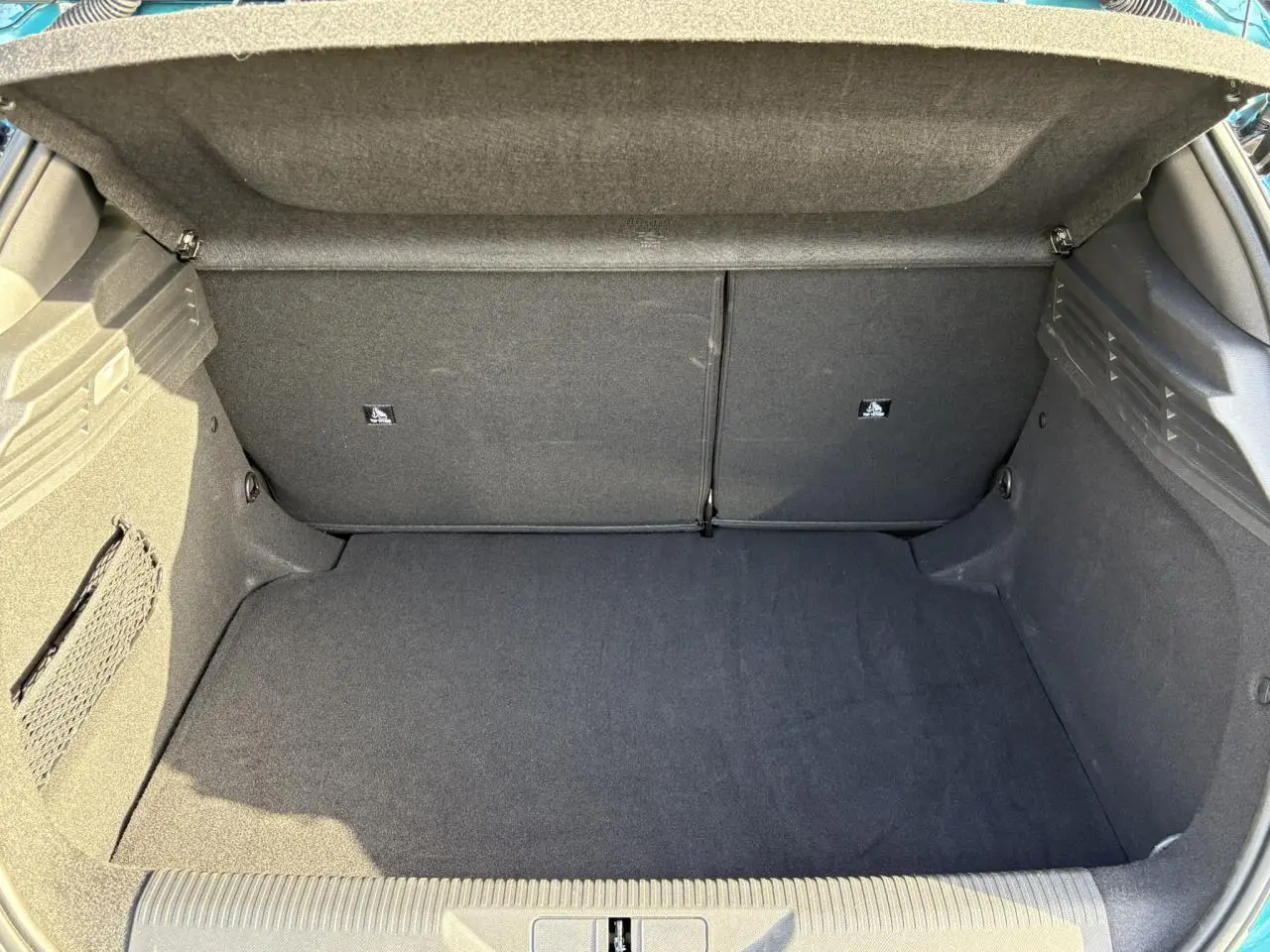 Vue intérieure du coffre spacieux et propre de la Peugeot 308 Hybrid 145 e-DCS6 Bleu Obsession, avec banquette arrière rabattue.