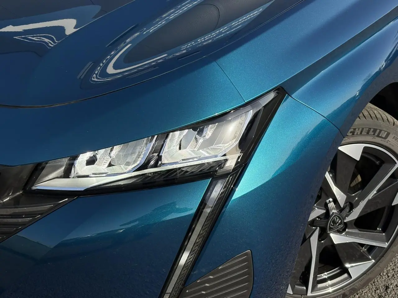 Gros plan sur le phare avant gauche et la jante alliage 17'' de la Peugeot 308 Hybrid Bleu Obsession.