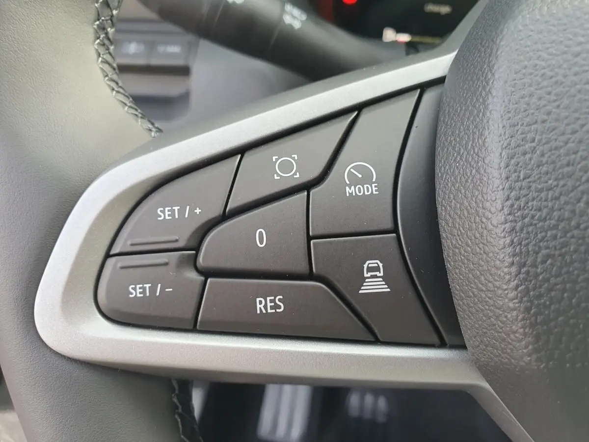 Gros plan sur les commandes de régulateur de vitesse au volant du Dacia Bigster, intérieur noir.