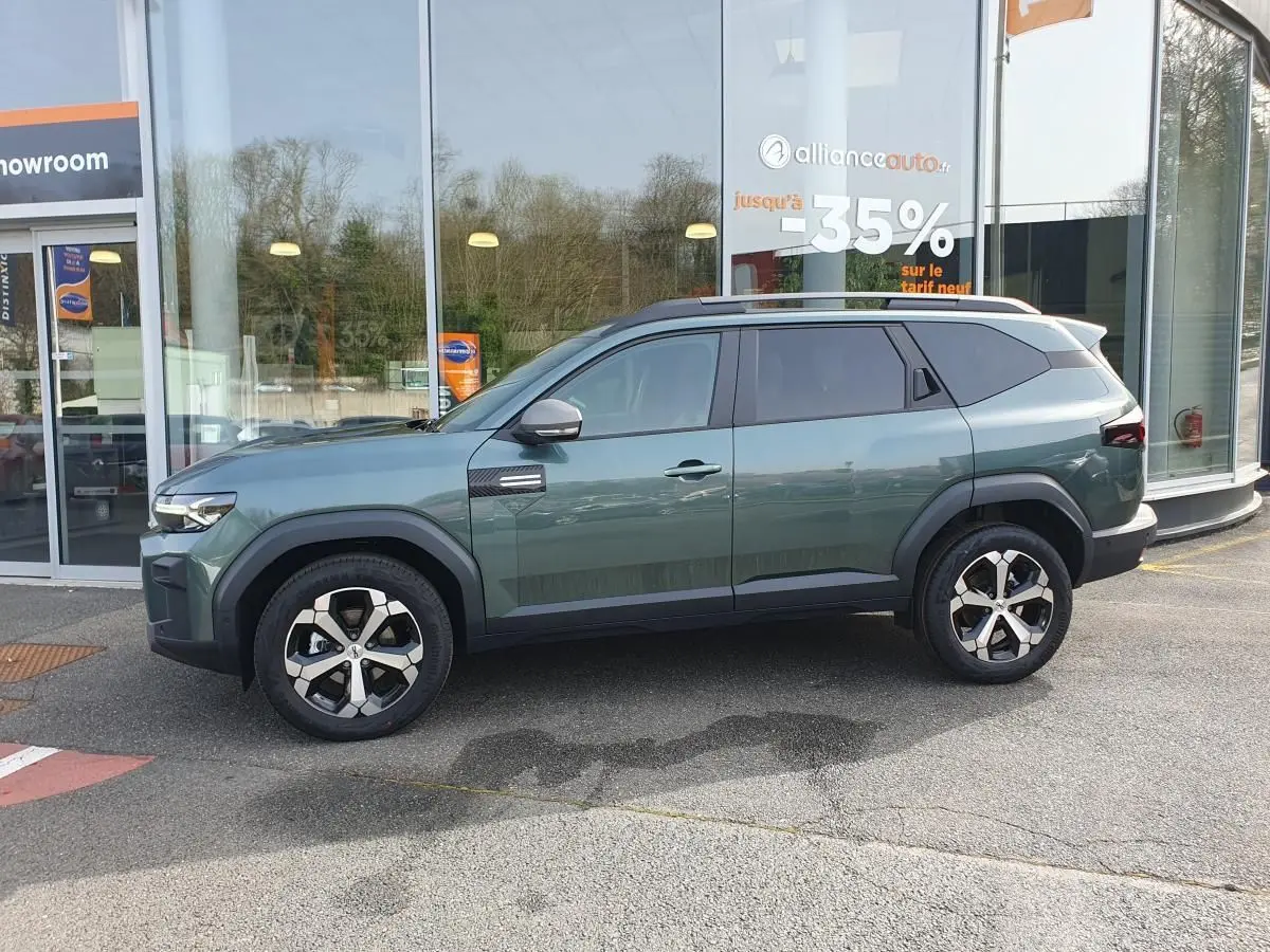 Vue de profil côté gauche du SUV Dacia Bigster vert cèdre avec jantes alliage 18” et toit panoramique visible.